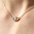 Gold-tone evil eye necklace worn at the collarbone with sparkling center moissanite