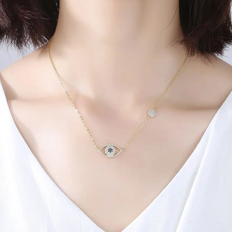 Gold-tone horizontal evil eye necklace worn at the collarbone with blue center stones and side station