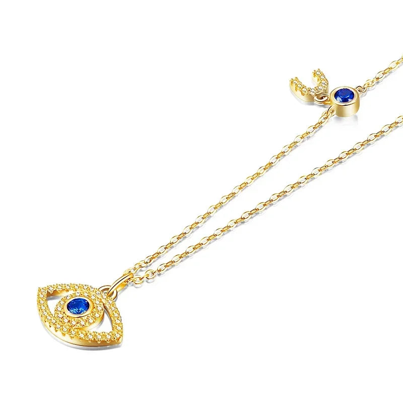 Close-up of the gold-tone evil eye pendant with blue CZ center and crescent accent on the cable chain