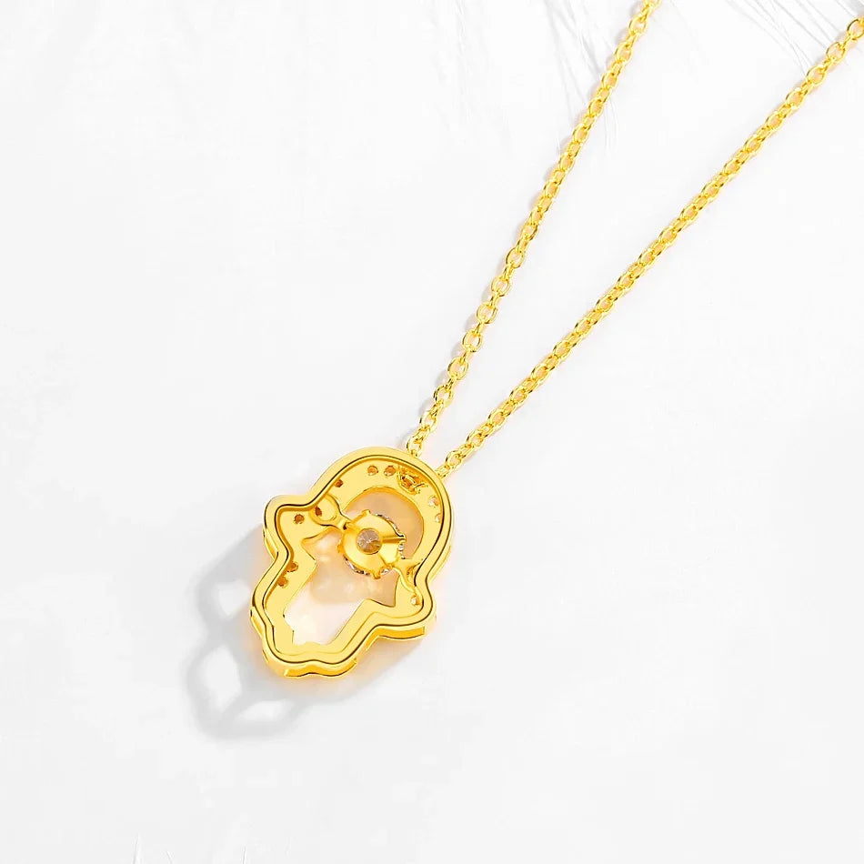Gold-tone open hamsa necklace shown from the back with an oval-link chain and raised center stone setting