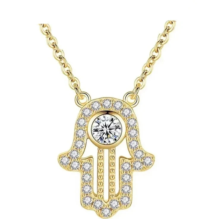 Gold hamsa hand necklace with a round CZ stone, stone-set border, and beaded open palm on white