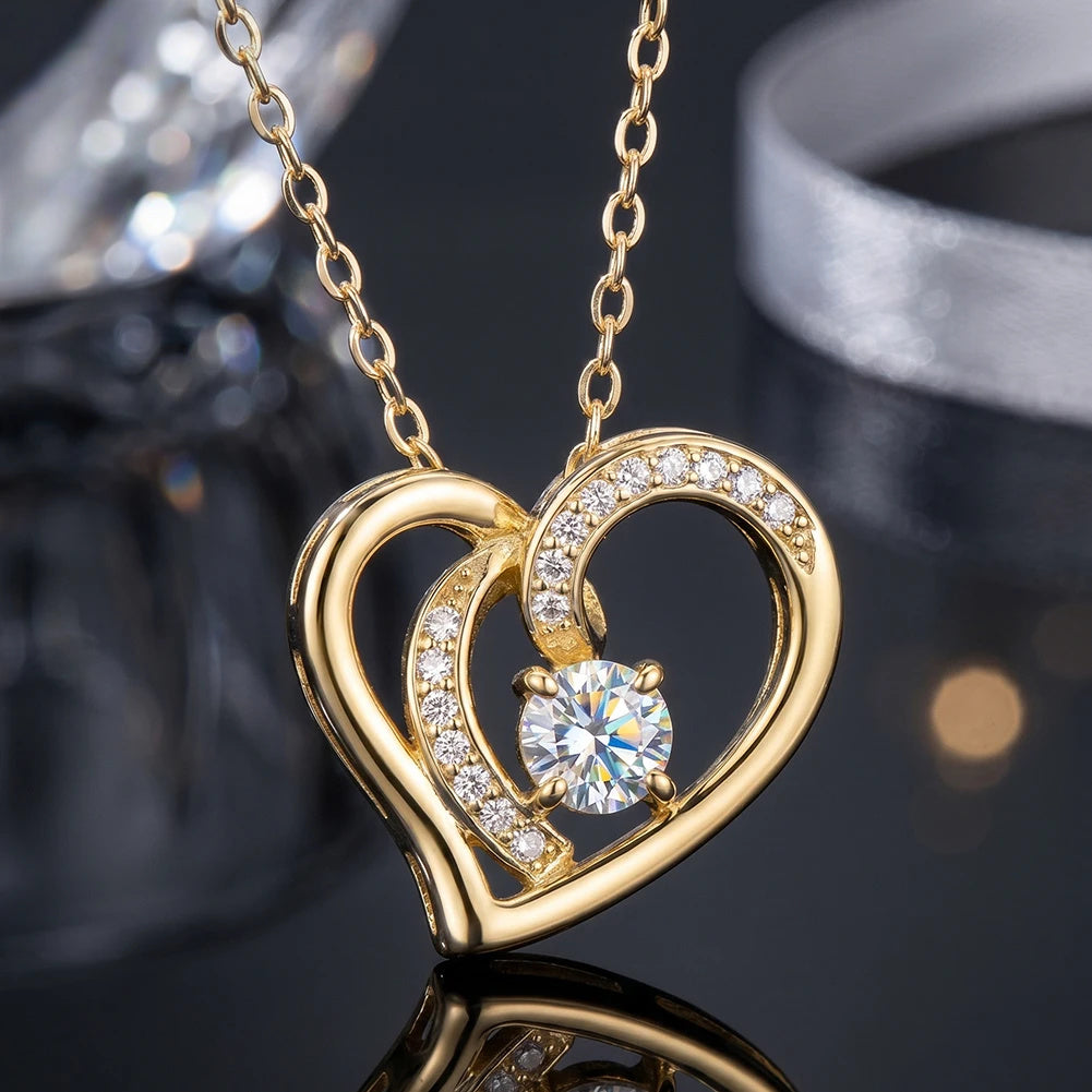 Gold-tone heart necklace close-up with polished crossing curves and a four-prong round moissanite center