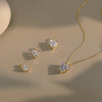 Gold-tone heart pendants in several sizes beside a matching clear heart necklace on a neutral surface