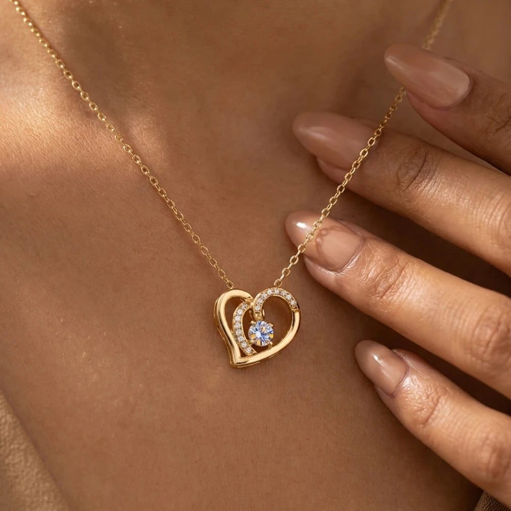 Close view of gold-tone overlapping heart necklace worn on the neck with stone-lined inner curve
