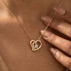 Close view of gold-tone overlapping heart necklace worn on the neck with stone-lined inner curve