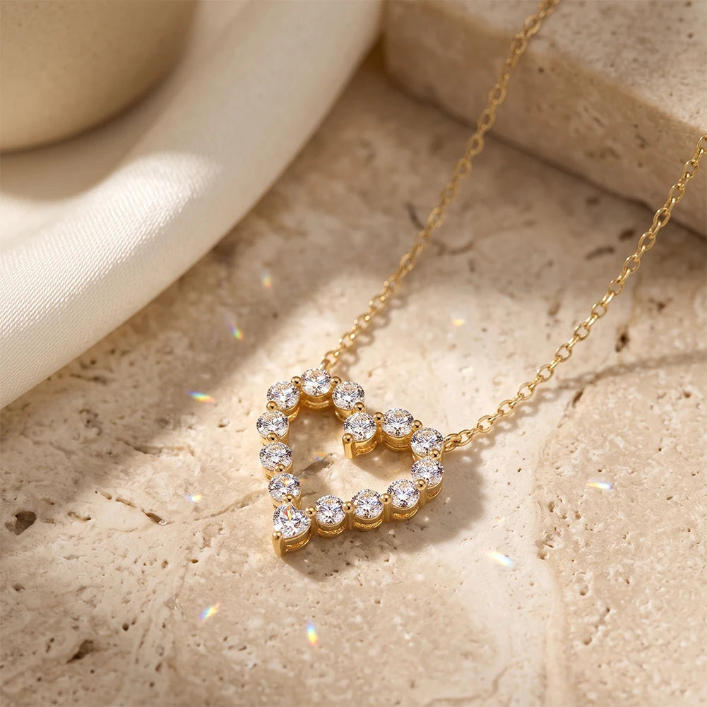 Angled view of a gold-tone hollow heart pendant with round stones and heart-shaped point