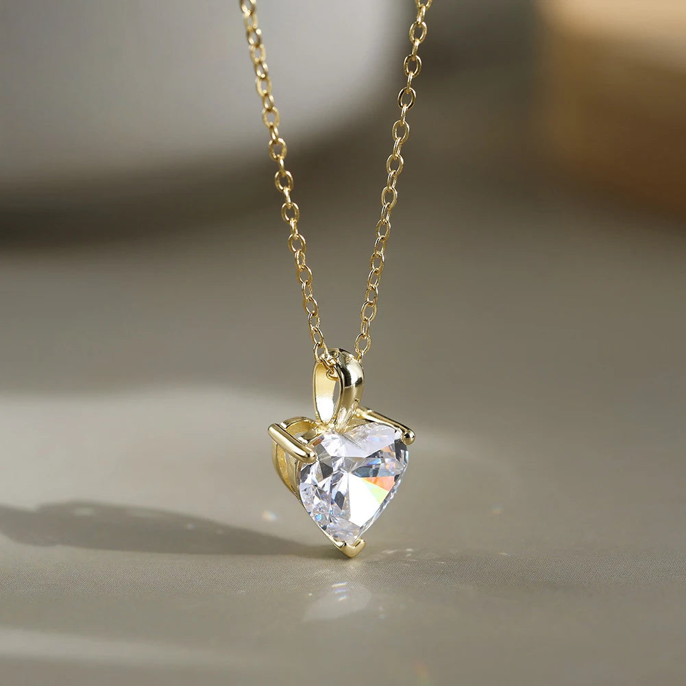 Gold-tone heart moissanite necklace shown in close-up with three-point setting and oval-link chain