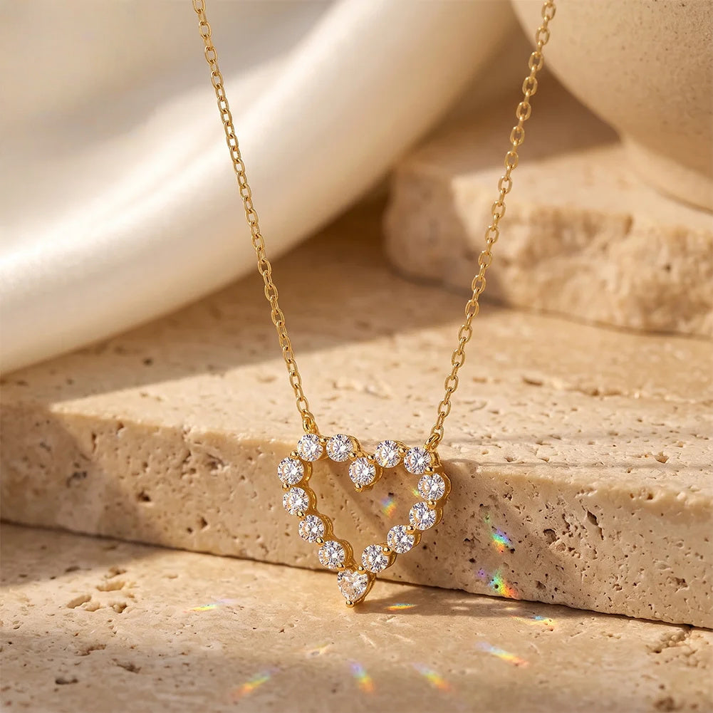 Gold-tone moissanite heart necklace hanging over layered stone blocks with an open center