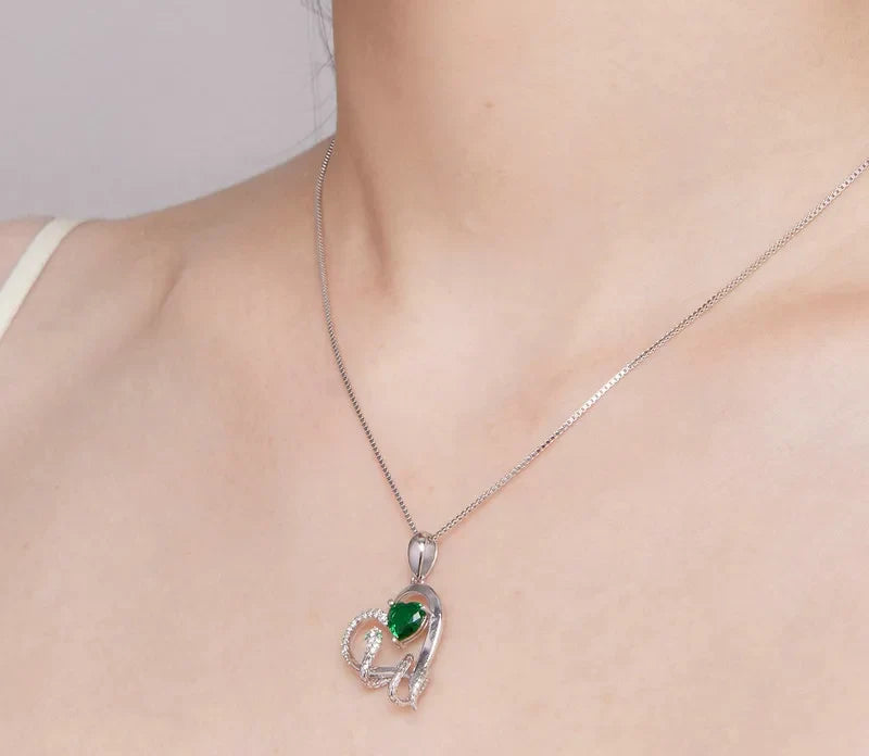 Angled neck view of the silver-colored snake pendant with its vivid green heart stone