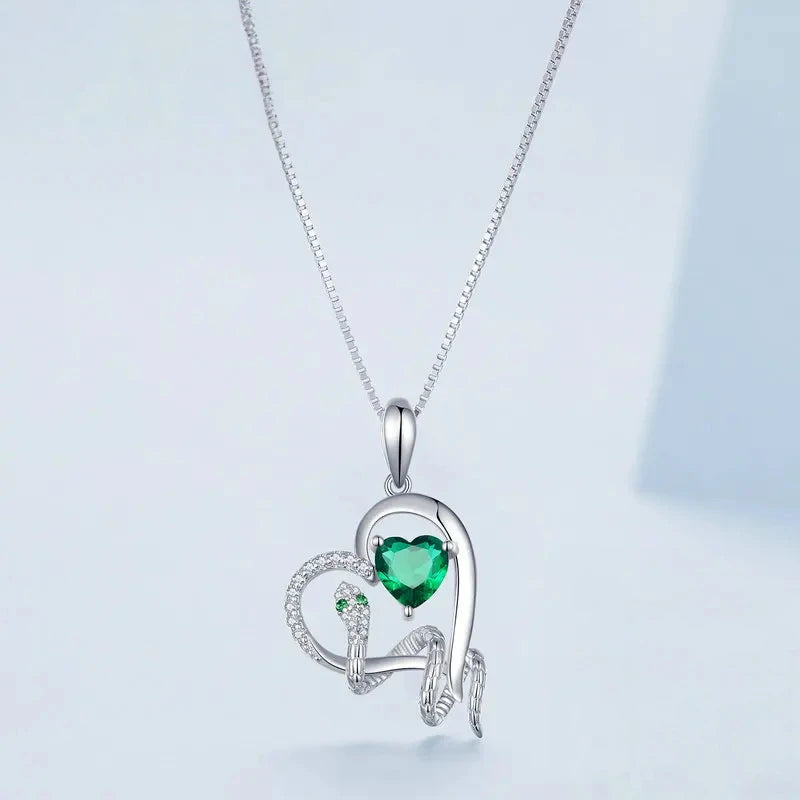 Close view of the coiled snake pendant with green heart cubic zirconia and clear stone details