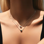 Green CZ heart necklace worn layered at the collarbone with a clear heart necklace