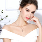 Rose gold-colored hamsa evil eye necklace worn at the base of the neck with an off-shoulder white top