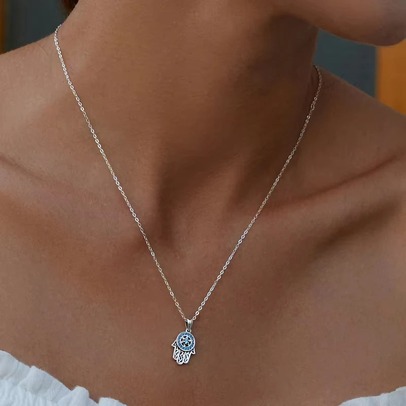 925 sterling silver hamsa necklace worn on the neck with a blue stone halo and star center