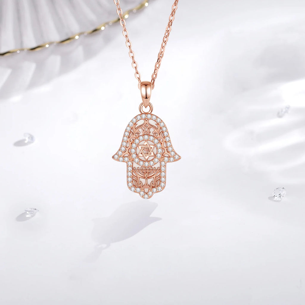 Rose gold Hamsa pendant hanging from a fine chain with clear CZ stone outline and filigree