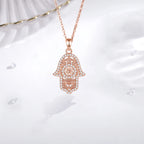 Rose gold Hamsa pendant hanging from a fine chain with clear CZ stone outline and filigree