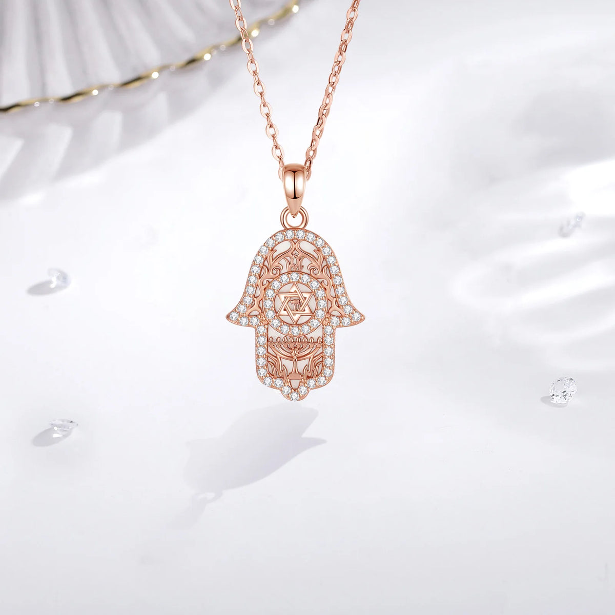 Rose gold Hamsa pendant hanging from a fine chain with clear CZ stone outline and filigree
