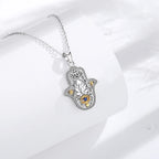 Detailed hamsa pendant necklace on a white display block, showing the lotus and blue eye centerpiece