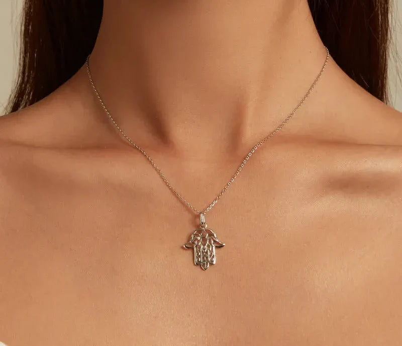 Openwork hamsa hand pendant worn on the neck, with a lotus flower and layered teardrop petals