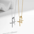 Hanging silver-tone and gold-tone double cross pendants showing separate bails and clear CZ stones