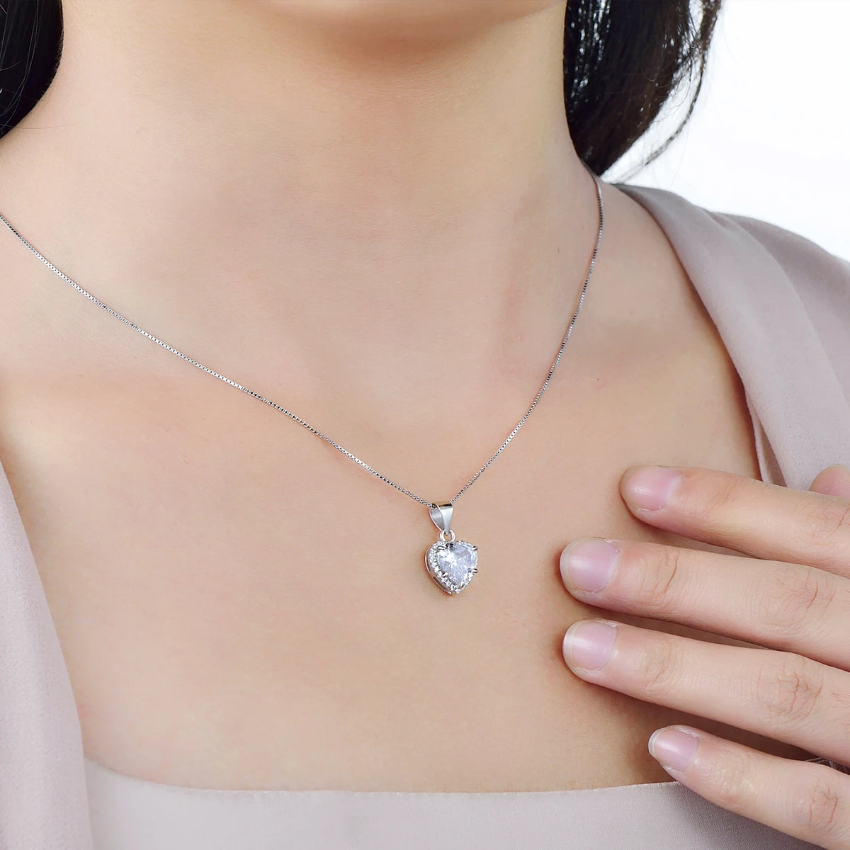Sterling silver heart halo necklace worn at the collarbone with a clear cubic zirconia center