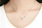 Small heart lock and key necklace worn at the base of the neck on a silver cable chain