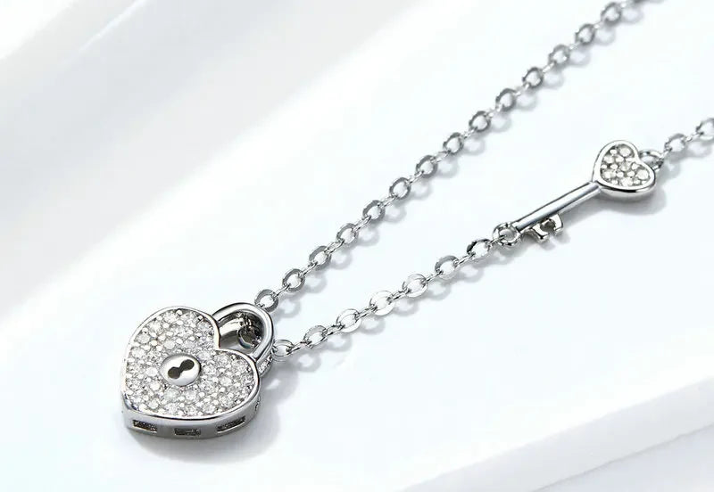 Platinum-plated sterling silver heart lock necklace laid across a white display block