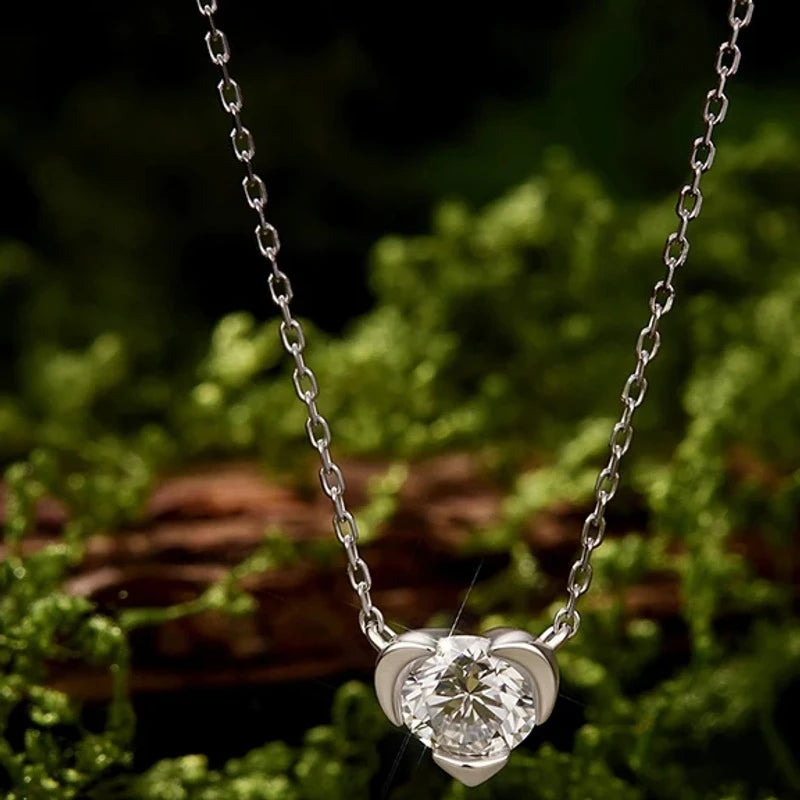 White gold plated sterling silver heart pendant with a round moissanite on green moss