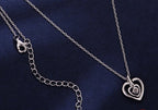 Back view of the nested heart necklace showing the lobster clasp, extender chain, and 925 charm on dark blue fabric
