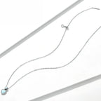 Full sterling silver necklace flat lay showing the fine oval-link chain, clasp, and pale-blue heart pendant