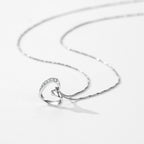 Sterling silver open heart pendant lying flat with a CZ stone curve and box-link chain