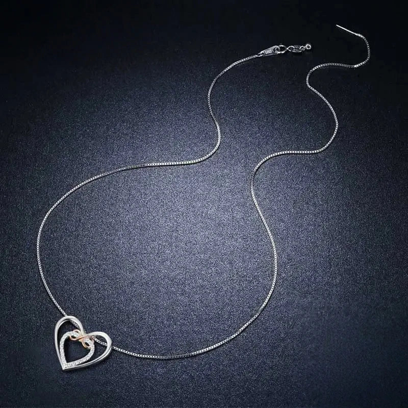 Full sterling silver necklace laid out on a dark surface, showing the box chain and heart pendant