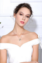 Woman in a white off-shoulder top wearing the hand in hand heart necklace