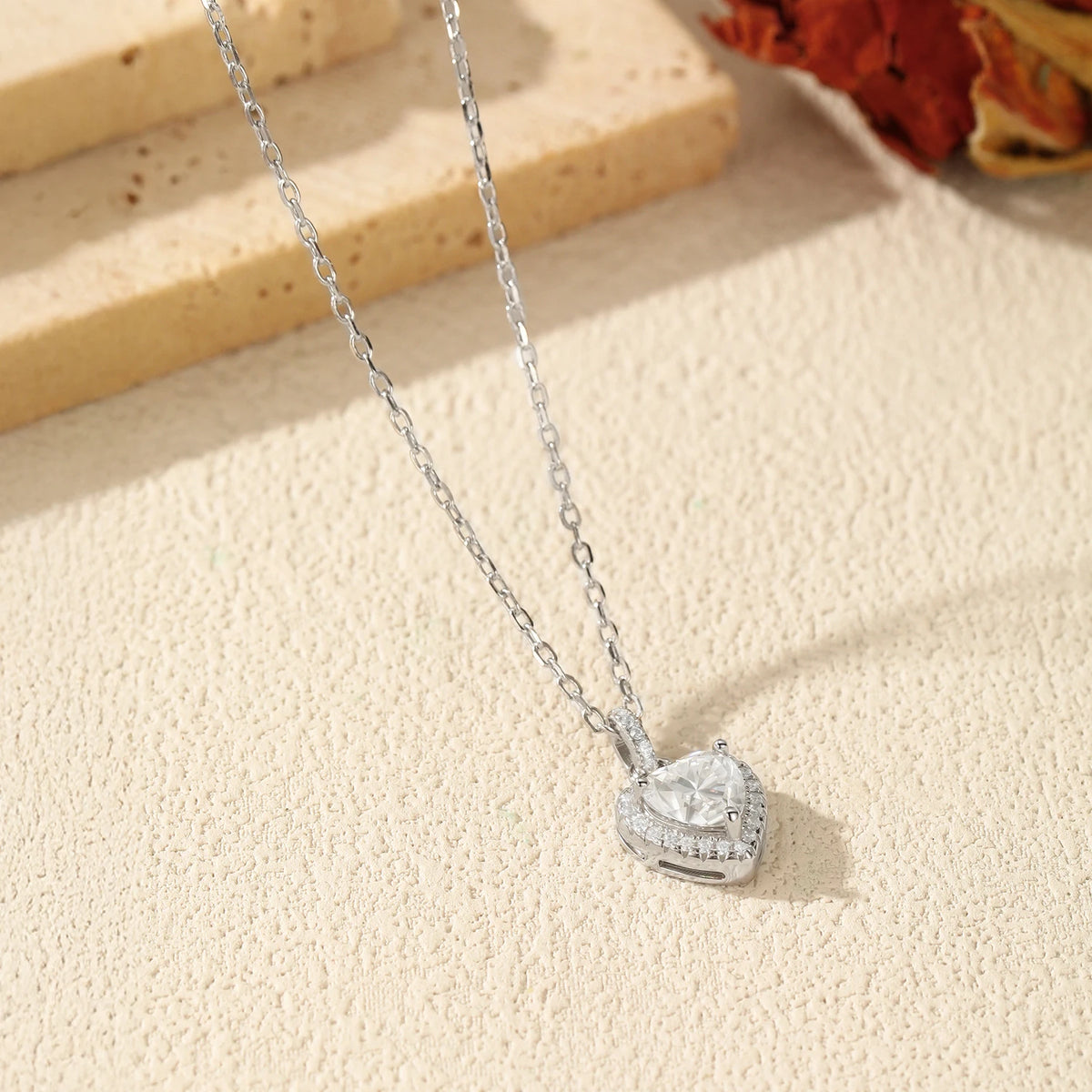 925 sterling silver heart necklace resting on a textured surface, showing the raised halo setting