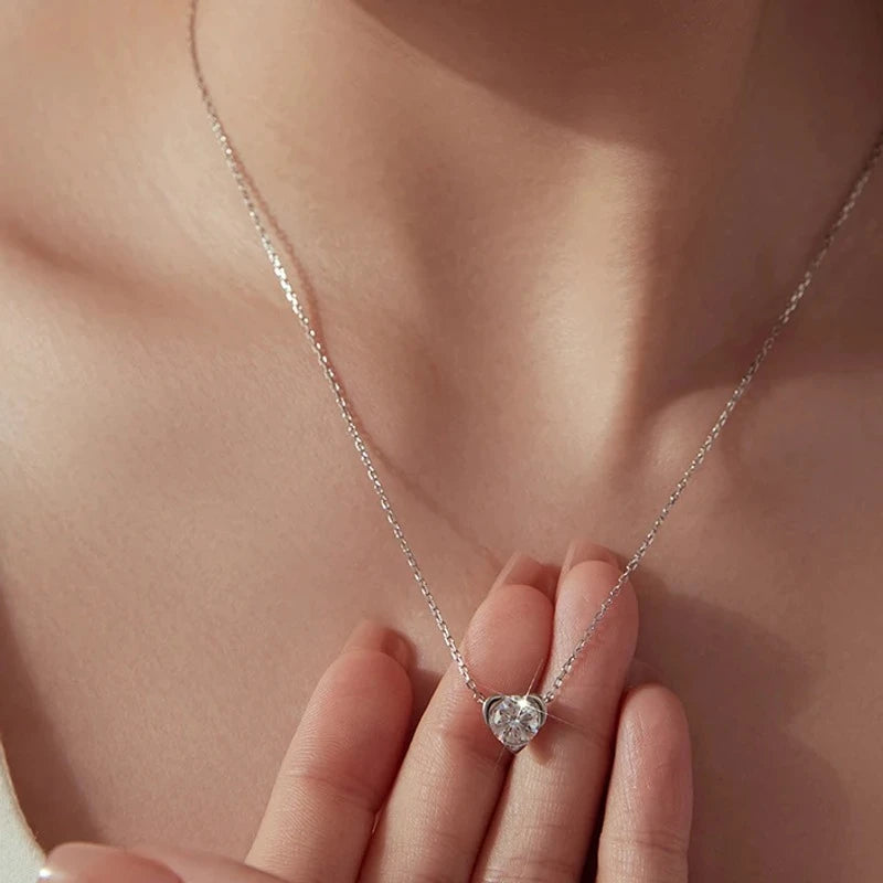 Silver-tone heart necklace with a round moissanite pendant worn at the base of the neck