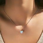 Sterling silver heart necklace worn at the collarbone with pale blue enamel and a multicolored center stone