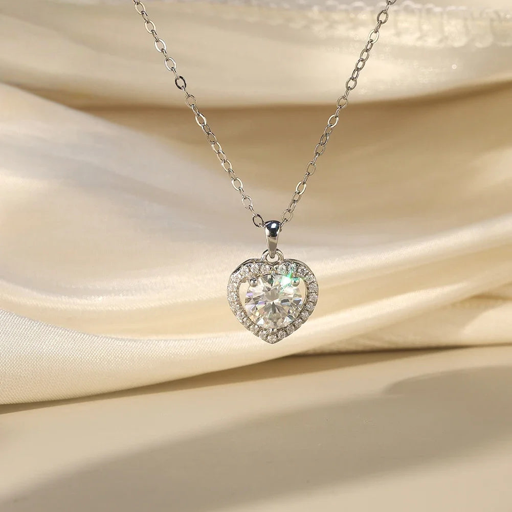 Silver heart pendant with round moissanite center and halo stones against draped satin