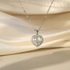 Silver heart pendant with round moissanite center and halo stones against draped satin