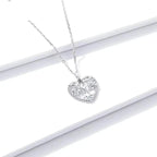 Platinum-plated sterling silver heart tree necklace displayed on a white surface with a rope-textured edge