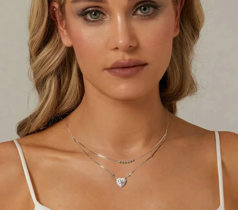 Layered sterling silver heart necklace worn at the neckline, with bead details and a moissanite heart