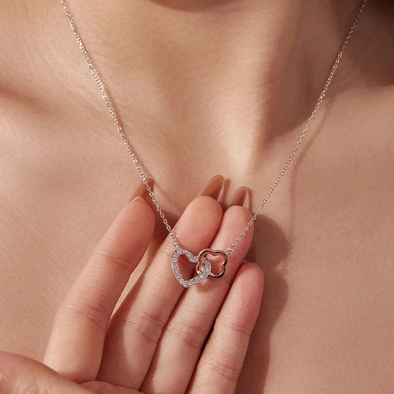 Linked rose gold and white gold-plated hearts with CZ stones held against the neck