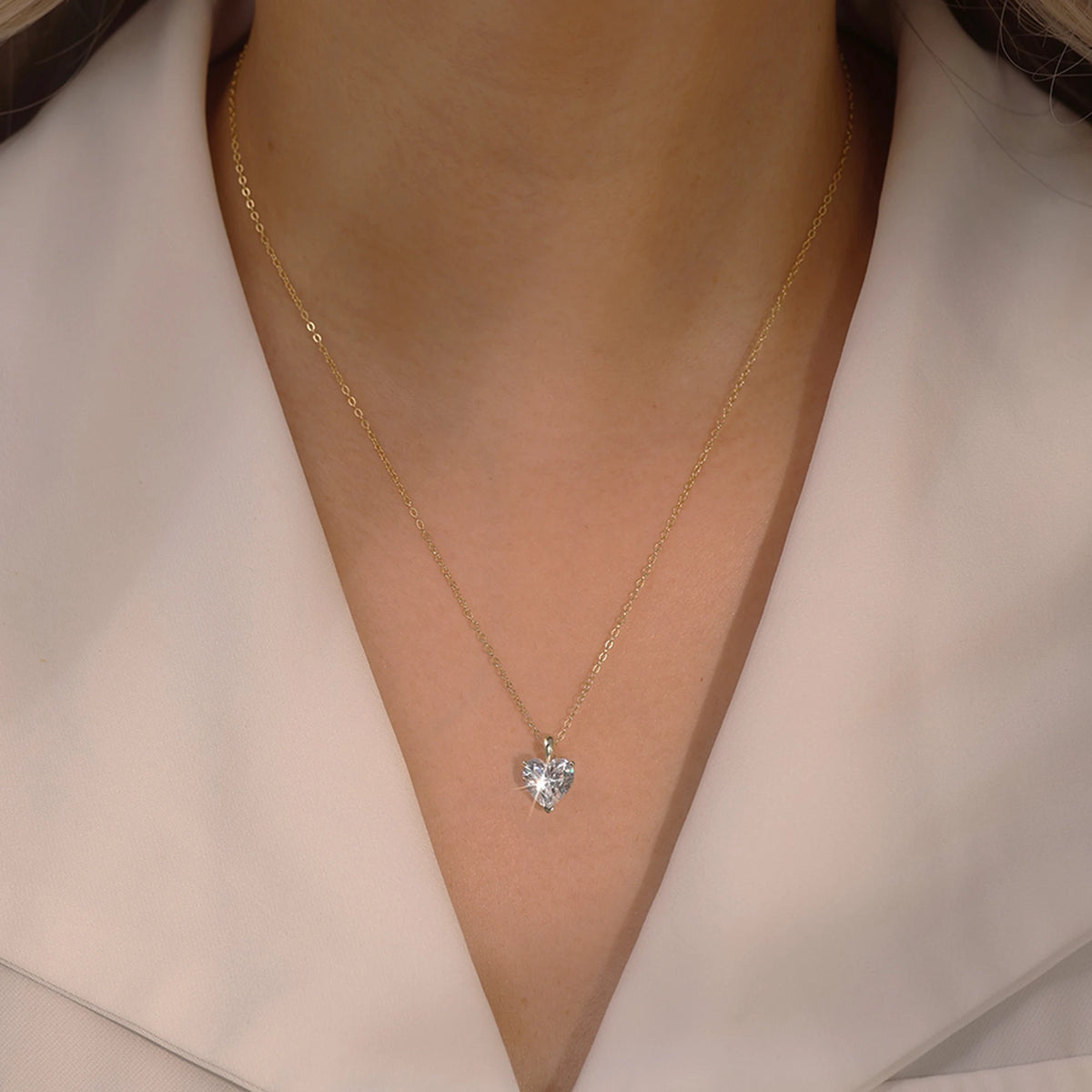 Medium gold-tone clear heart necklace worn with the pendant centered below the collarbone