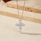 Close-up of the six round moissanite stone cross pendant on an elongated-link chain over a textured surface