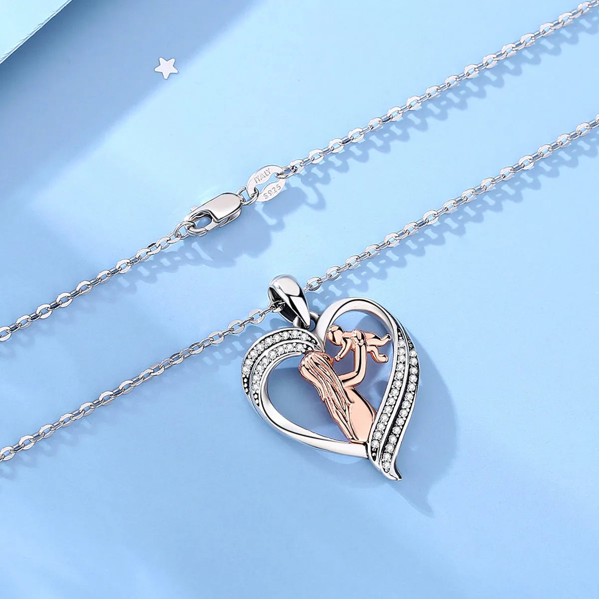 Mother and baby heart necklace laid on a blue surface with oval-link chain and lobster clasp