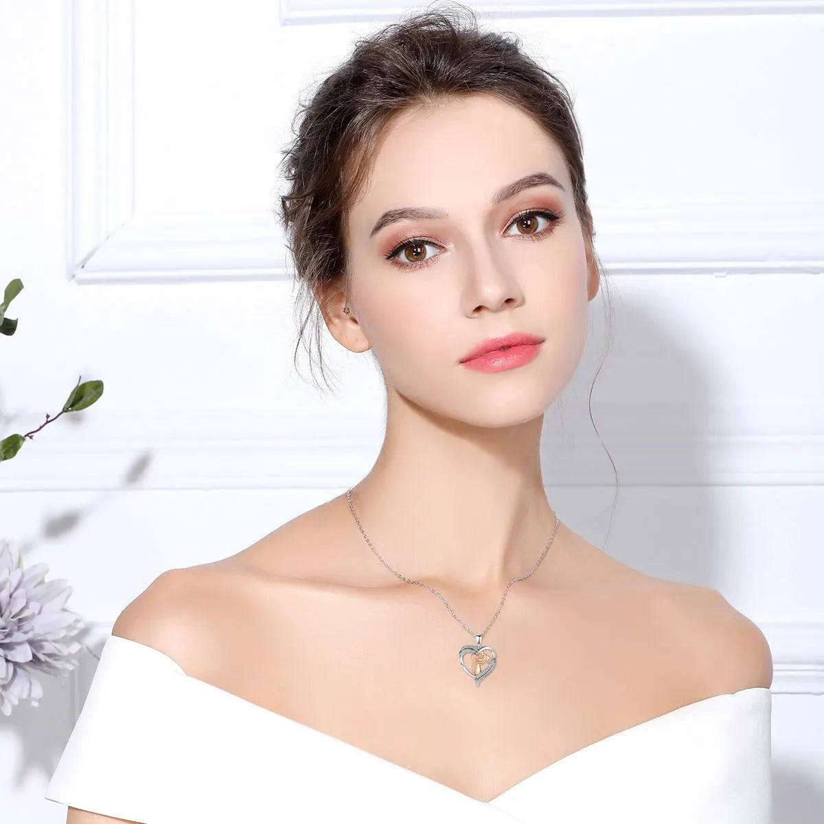 Woman wearing the mother and baby heart necklace centered below the collarbone