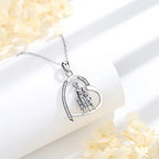Open heart pendant with mother and two children resting on a white display block beside pale flowers