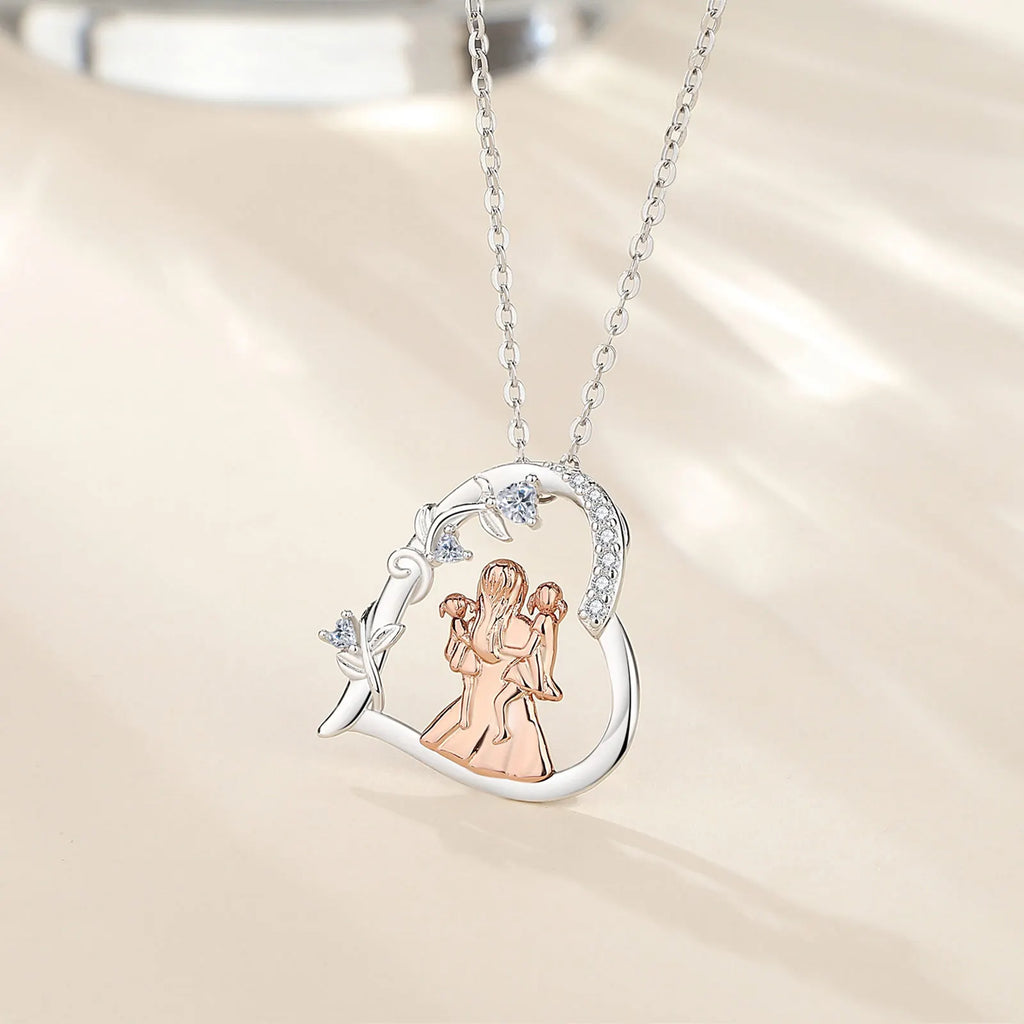 Mother and two daughters heart pendant hanging from an oval-link chain against a softly lit background