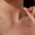 Nested heart necklace in 925 sterling silver with moissanite, worn high on the neck with a hand holding the chain