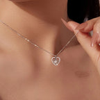 Nested heart necklace in 925 sterling silver with moissanite, worn high on the neck with a hand holding the chain
