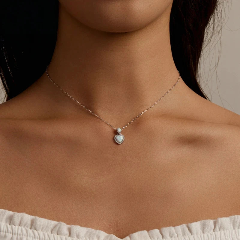 Small pale-blue opal-look heart necklace worn at the base of the neck with a sparkling stone outline
