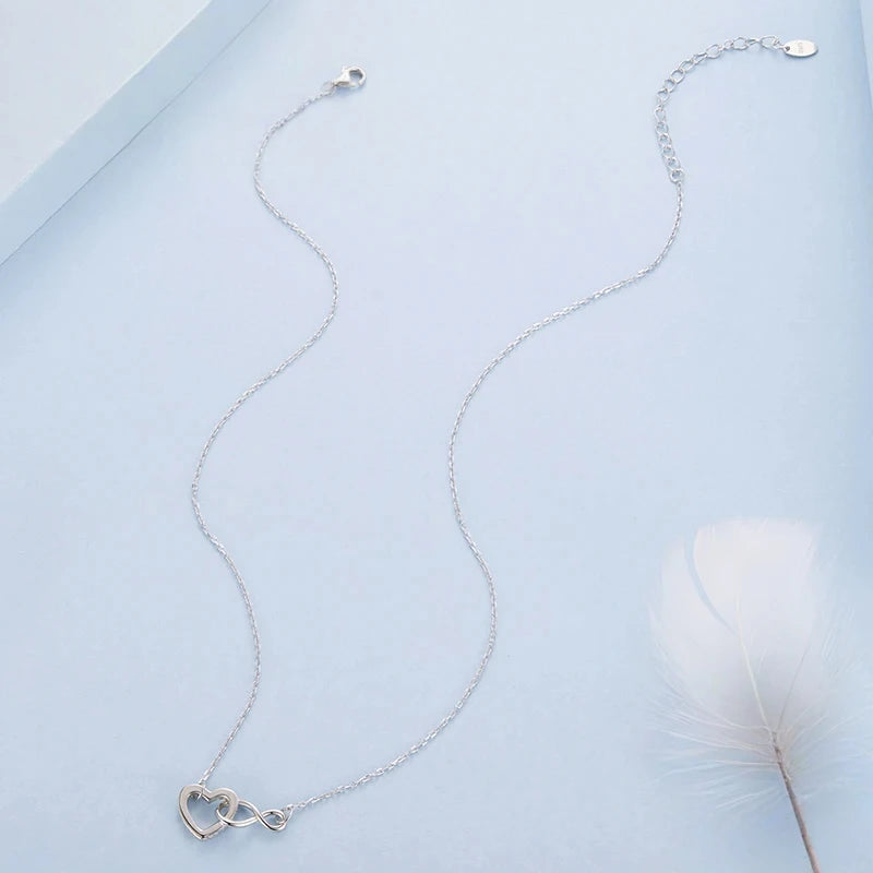 Full white gold-plated sterling silver necklace laid out with its open heart infinity pendant